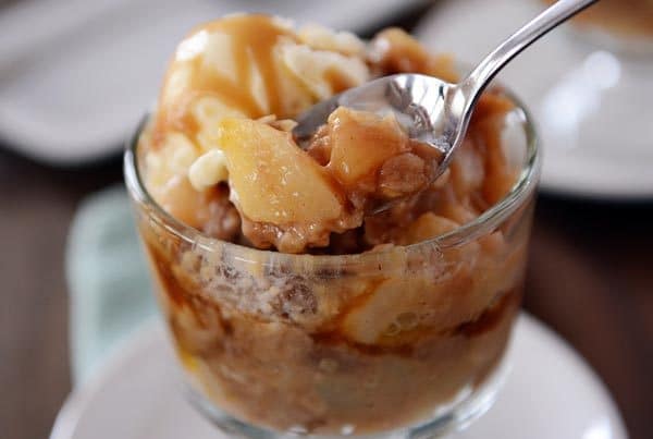 Spoon taking a bite out of a caramel pear crisp. 