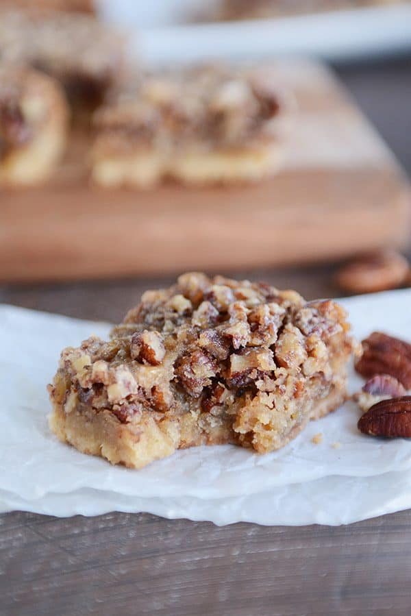 A pecan pie bar with a bite taken out.