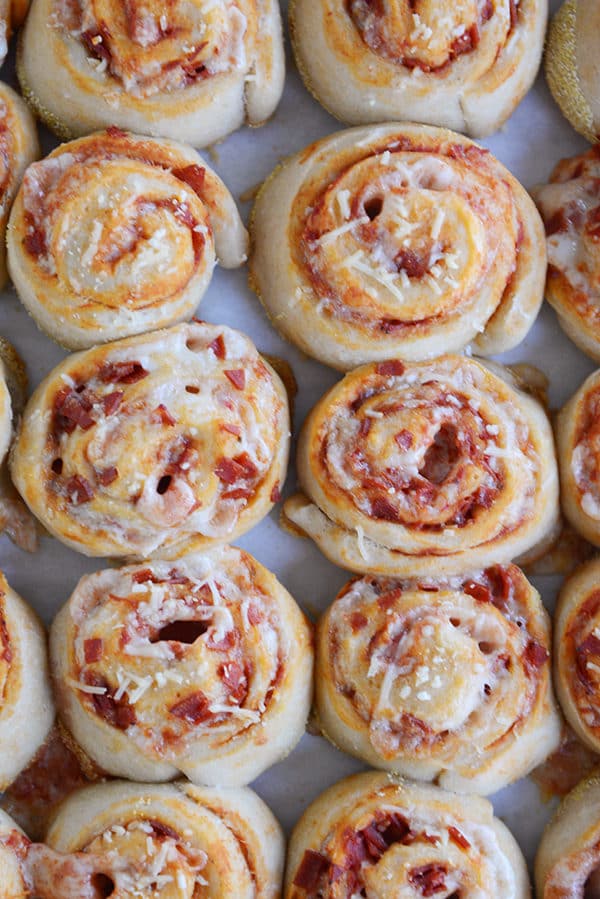 A cookie sheet filled with pepperoni pizza pinwheels.