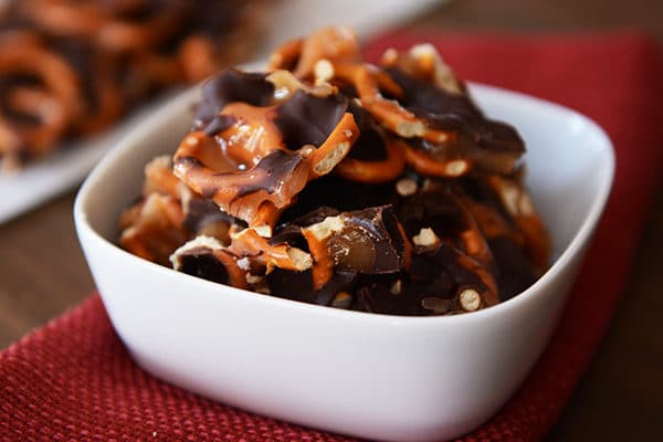 A white ramekin full of chunks of chocolate caramel pretzel bark. 