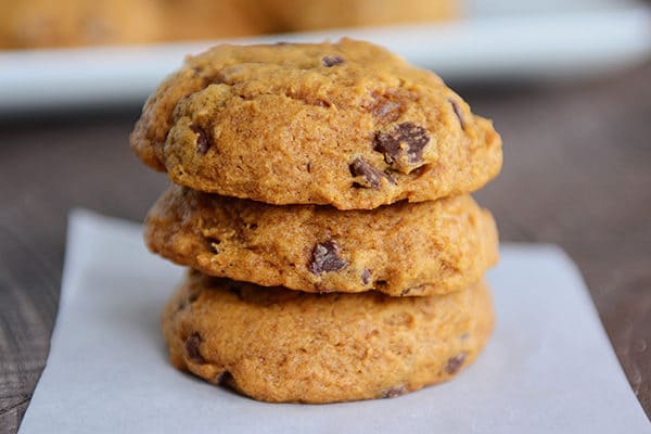Three cakey pumpkin chocolate chip cookies stacked on top of each other. 