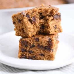 Two pieces of pumpkin chocolate chip snack cake stacked with bite taken out.