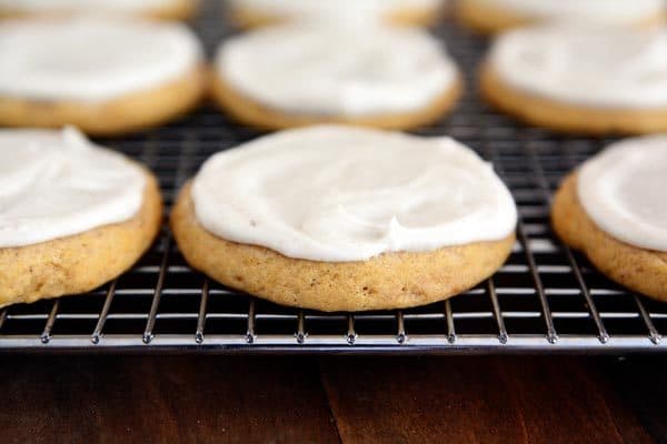 Frosted pumpkin sugar cookies on a cooling rack. 