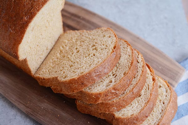 A loaf of sliced whole wheat bread on a cutting board.