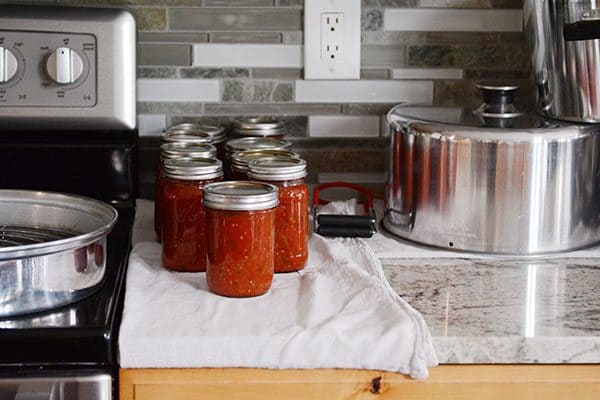 Canned salsa on a white towel on a kitchen countertop. 