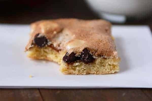 A meringue topped chocolate chip bar with a bite taken out.