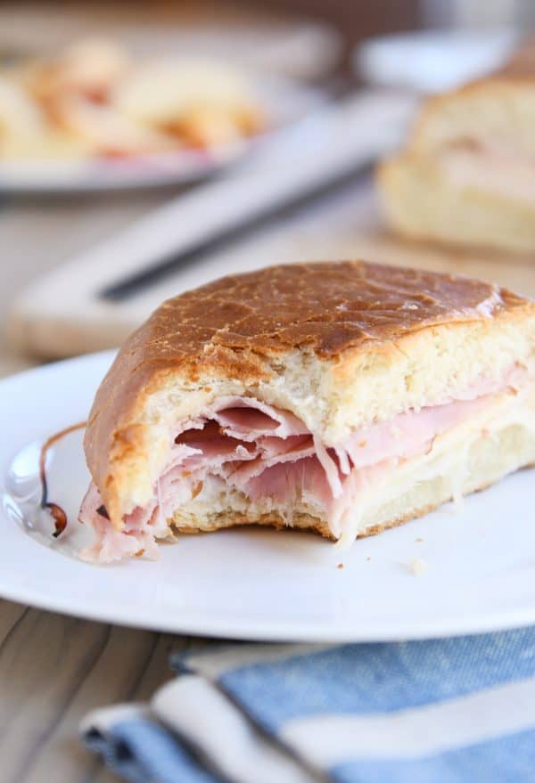 Bite taken out of ham and cheese sheet pan panini.