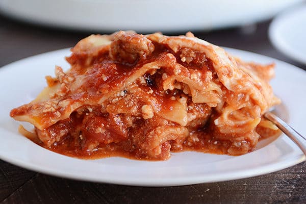 A white plate full of a big helping of cheesy red sauce lasagna. 