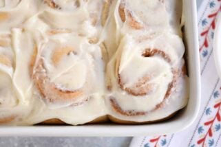 Small batch cinnamon roll recipe with dough baked and frosted in white pan.