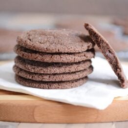 Stack of chocolate sugar cookies on a white napkin with one in half.
