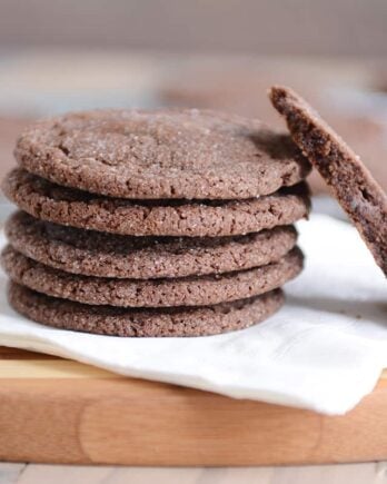 Stack of chocolate sugar cookies on a white napkin with one in half.