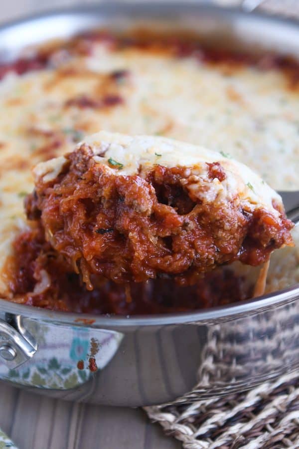 Scoop of Spaghetti squash spaghetti bake topped with cheese in pan.