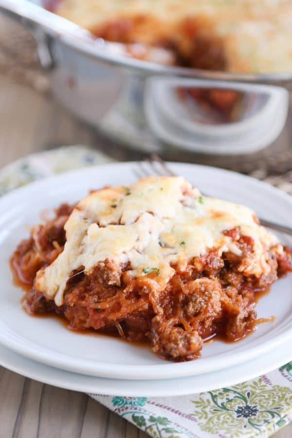 Scoop of Spaghetti squash spaghetti bake topped with cheese on a white plate.