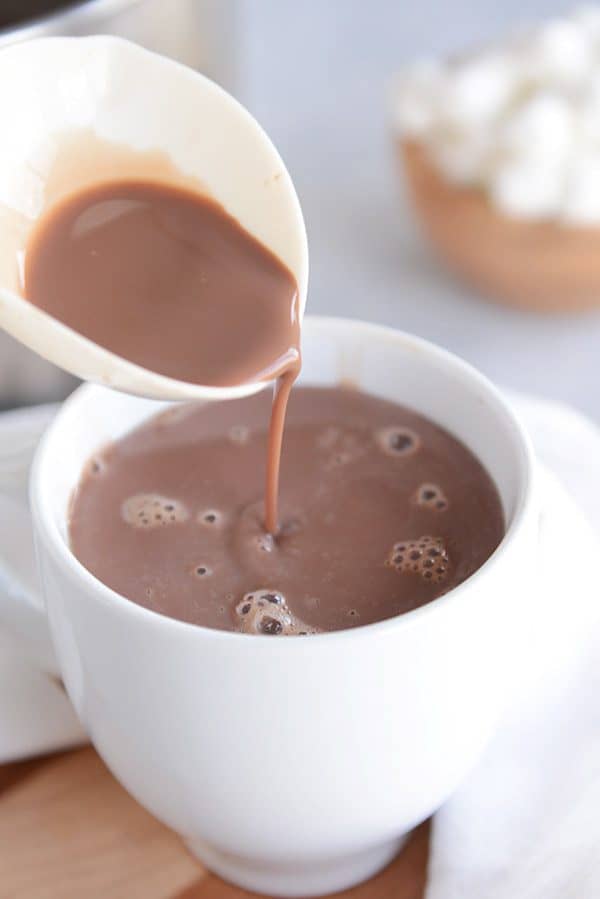 A ladle of hot chocolate being poured in a white mug.