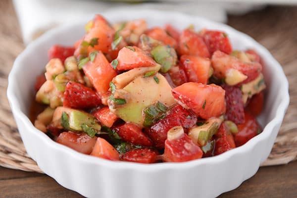 A white ramekin full of strawberry avocado salsa. 