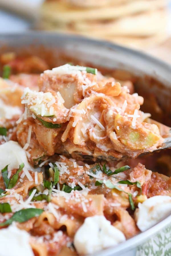Spoon full of skillet vegetable lasagna cooked in stainless skillet with dots of ricotta cheese. 