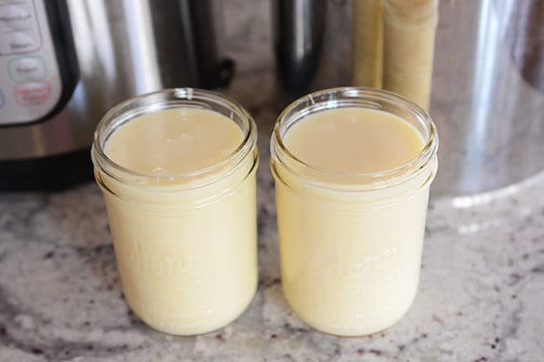 Two glass mason jars full of sweetened condensed milk. 