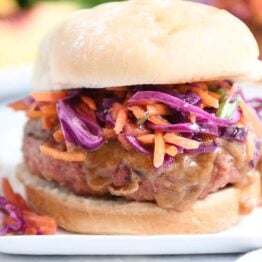 Close up of Thai burgers with peanut sauce and tangy slaw.