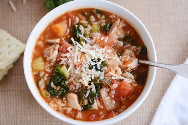 A white bowl of turkey and brown rice soup topped with parmesan cheese.