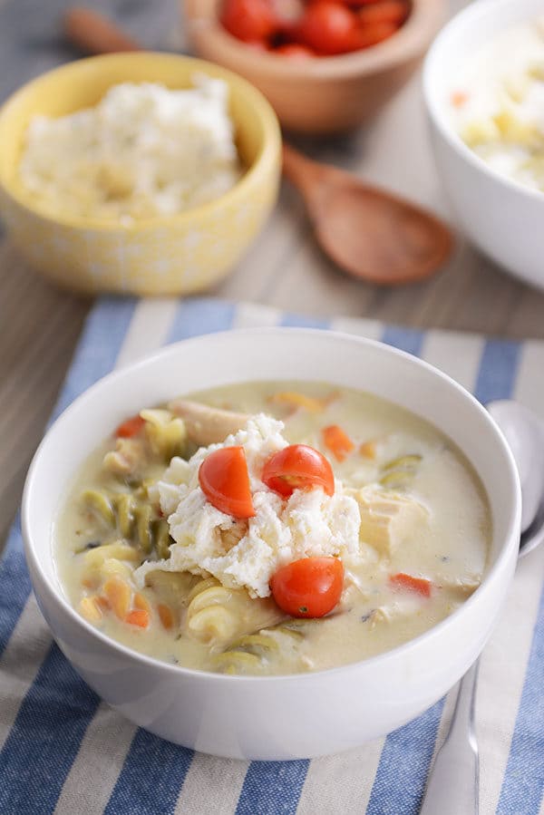 A bowl of creamy lasagna soup topped with a ricotta cheese mixture and chopped cherry tomatoes.