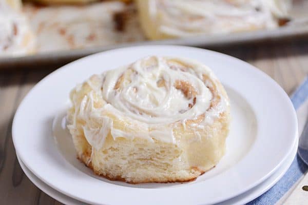 a frosted cinnamon roll on a white plate