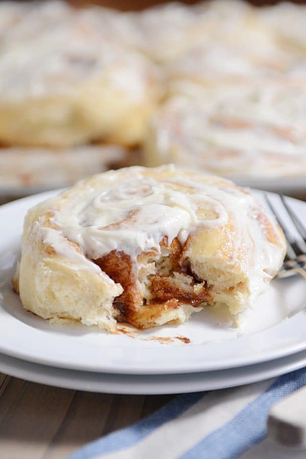 A frosted cinnamon roll with a bite taken out. 