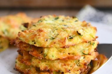 Cheesy baked zucchini bites stacked on a spatula.