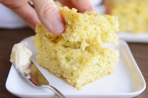 A thick piece of fluffy zucchini cornbread being split in half. 