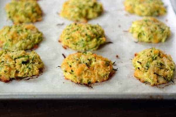 Four Baked Cheesy Zucchini Bites stacked on a white ramekin.