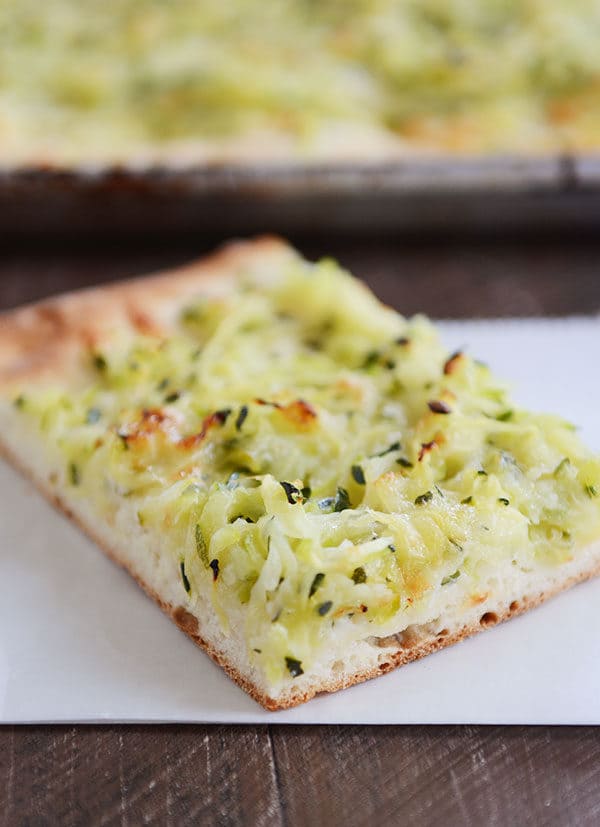 A large piece of zucchini-topped pizza on a white napkin.